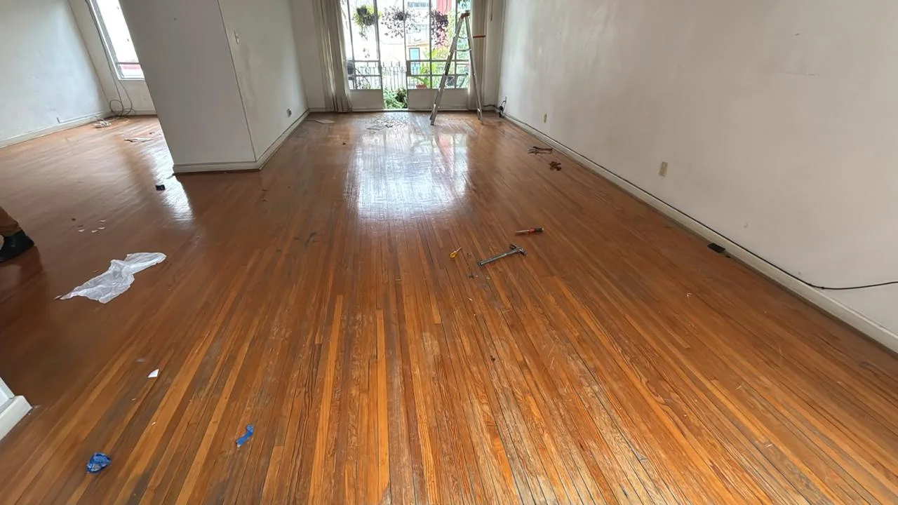 Habitación con piso de madera opaco y desgastado antes de renovarse